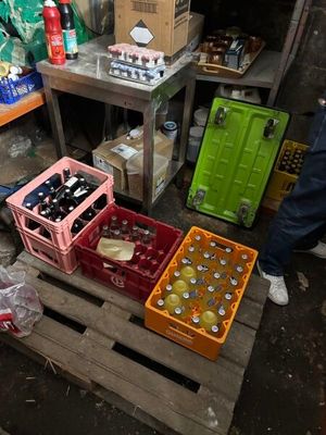 un homme debout à côté de caisses de sodas et de bière