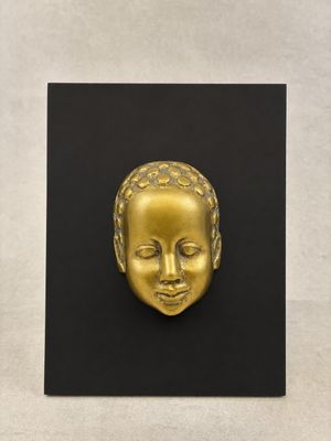 a gold sculpture of a child ' s face on a black surface