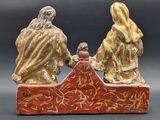 two figurines of people sitting on a bench with a bird perched on top of them