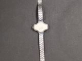 silver and white watch on a gray surface with a black background