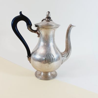 a silver tea pot with a black handle on a table