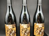 trois bouteilles de vin posées sur un bloc de bois