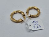 deux boucles d'oreilles en anneau dorées, avec une étiquette de prix, posées sur une surface blanche