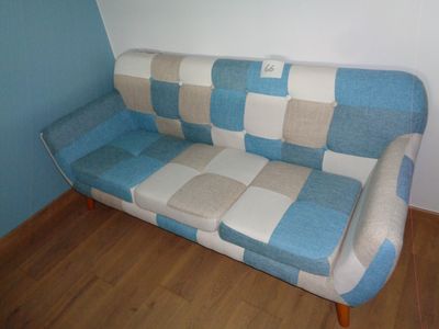 un canapé bleu et blanc dans une pièce avec du parquet