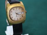 a gold and black watch on display on a green surface