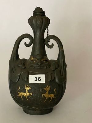 un vase noir orné de motifs dorés sur fond blanc