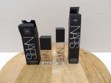 three bottles of nars cosmetics sitting on top of a wooden table
