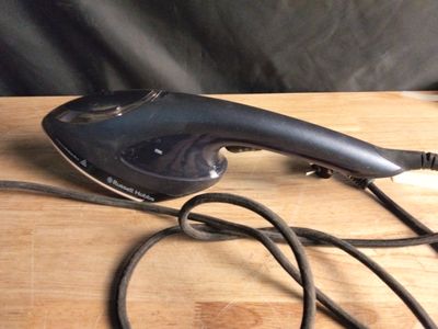 un fer à repasser à vapeur noir posé sur une table en bois