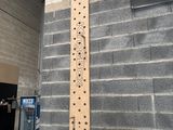 a wooden ruler hanging on a brick wall next to a sign