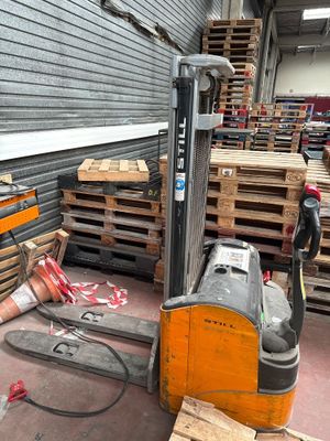 un chariot élévateur garé dans un entrepôt, à côté de palettes de bois