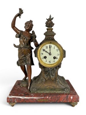 une statue représentant une femme tenant un oiseau à côté d'une horloge
