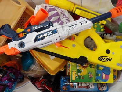a bunch of toys and a toy gun on a bed