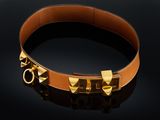 un bracelet en cuir marron orné de rivets dorés sur fond noir