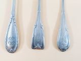 three spoons and a fork on a white surface