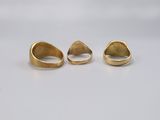 three gold rings on a white surface