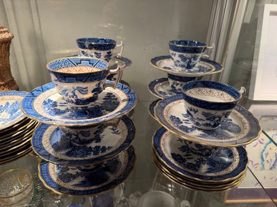 many blue and white plates and cups on a glass table