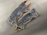 two pairs of blue jeans with leather handles on a metal surface