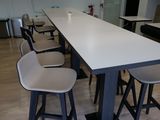 une longue table avec quatre tabourets et une télévision accrochée au mur