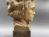 an image of a sculpture of a woman ' s head on a wooden stand