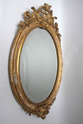 Miroir ovale en bois et stuc, sculpté et doré à décor de rin…