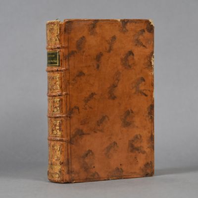 an old book with a brown cover sitting on top of a table