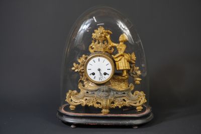 a gold clock under a glass dome on a black background