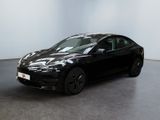 une Tesla Model S noire garée dans une pièce blanche au sol noir
