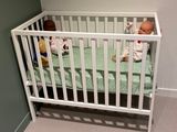 a baby in a crib next to a stuffed animal