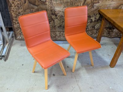 deux chaises orange placées l'une à côté de l'autre près d'une table