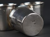 two silver cups sitting next to each other on a table