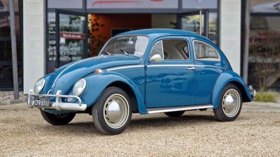 une Coccinelle VW bleue garée devant un immeuble