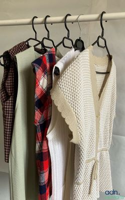 three sweaters hanging on a rack in front of a wall