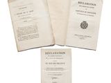 three old books sitting on top of each other on a white surface