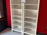 two white bookshelves in a room with a red wall