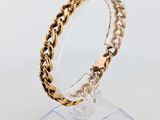 a close up of a gold bracelet on a clear stand