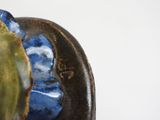 a close up of a blue and green vase on a white surface