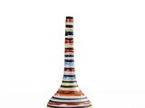 un vase à rayures multicolores posé sur une surface blanche