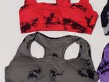 three women ' s sports bra tops are lined up on a white surface