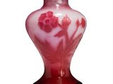 un vase rouge orné de fleurs, posé sur une surface blanche