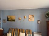 un salon avec un canapé, un fauteuil, une horloge et des tableaux accrochés au mur