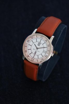 a close up of a watch on a black surface with a black background