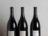 three bottles of wine are lined up on a wooden table