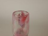 a glass with a pink substance inside of it on a table