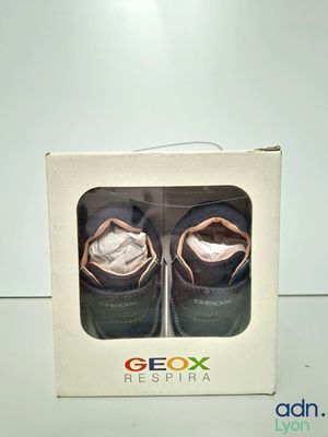 two pairs of baby shoes in a box on a table