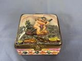 a small box with a painting on it on a blue surface