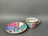 two cups and saucers with designs on them sitting on a table