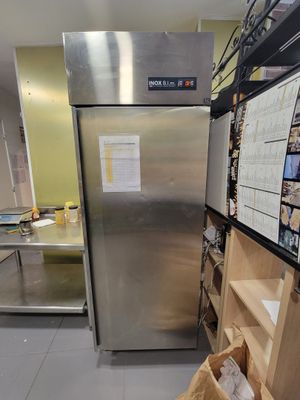 un réfrigérateur au milieu d'une cuisine, avec un sac en papier posé devant