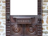 une armoire en bois surmontée d'un miroir, placée devant un mur en pierre