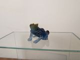 une petite figurine représentant une grenouille assise sur une table en verre