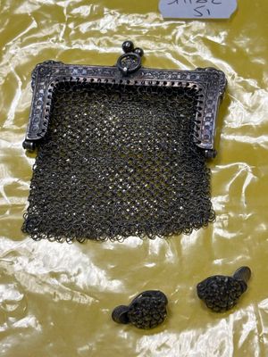 un sac à main noir entouré d'une chaîne, posé sur un fond jaune